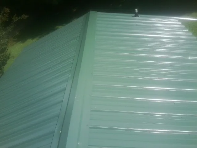 New green metal panels meeting at the ridge of a roof — Flat Roof Repair work by our crew in Mojave