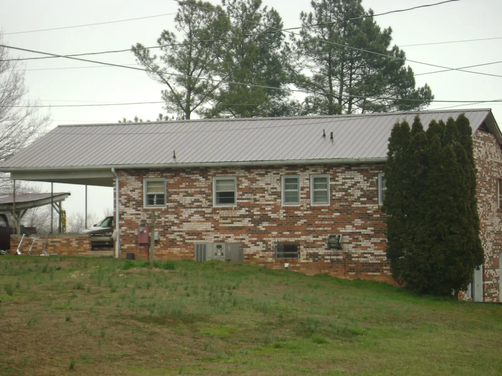 Gray metal roof on a brick split level home with a carport in Mojave