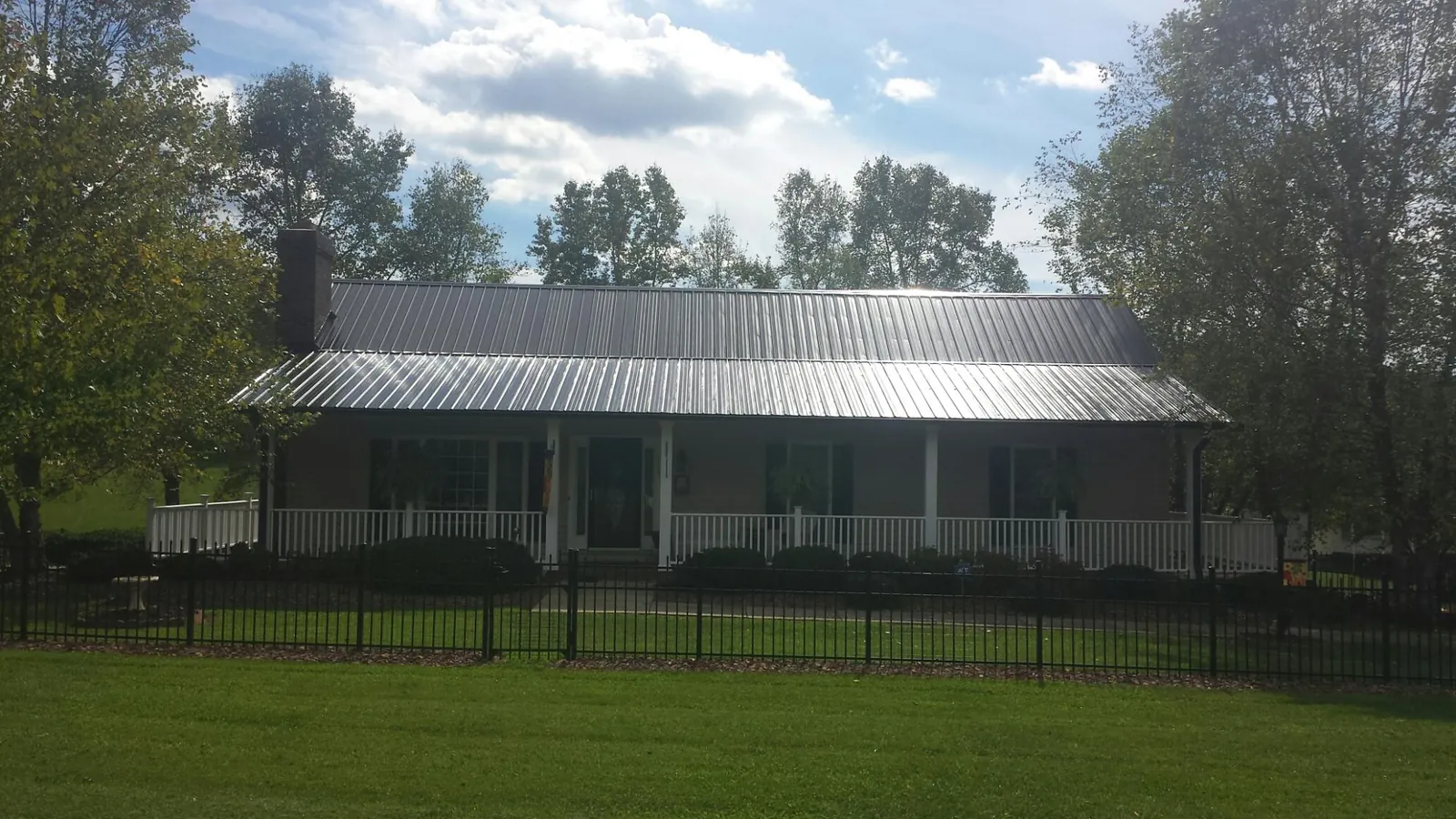 Gray metal roof on a brick ranch with a full width front porch — Gutter Guard Installation work by our crew in Mojave
