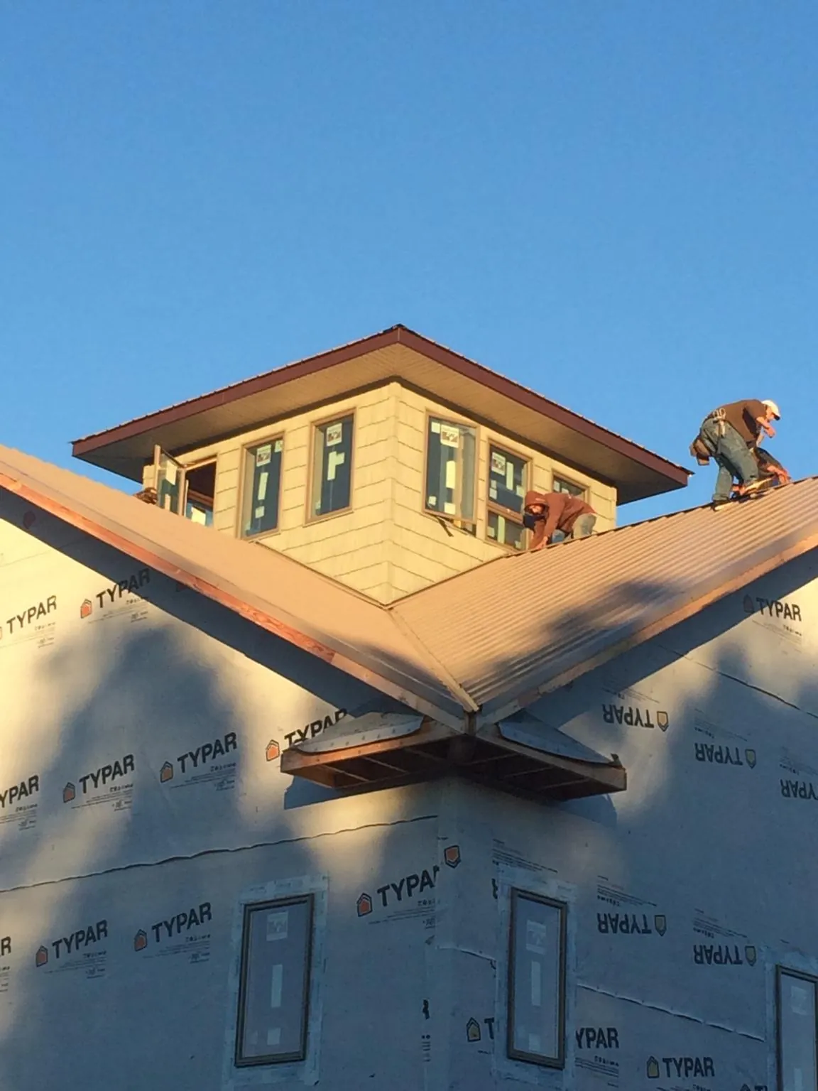 Roofers working around a rooftop cupola on a new metal roof at sunset — Roof Waterproofing in Mojave by Roofing Brothers